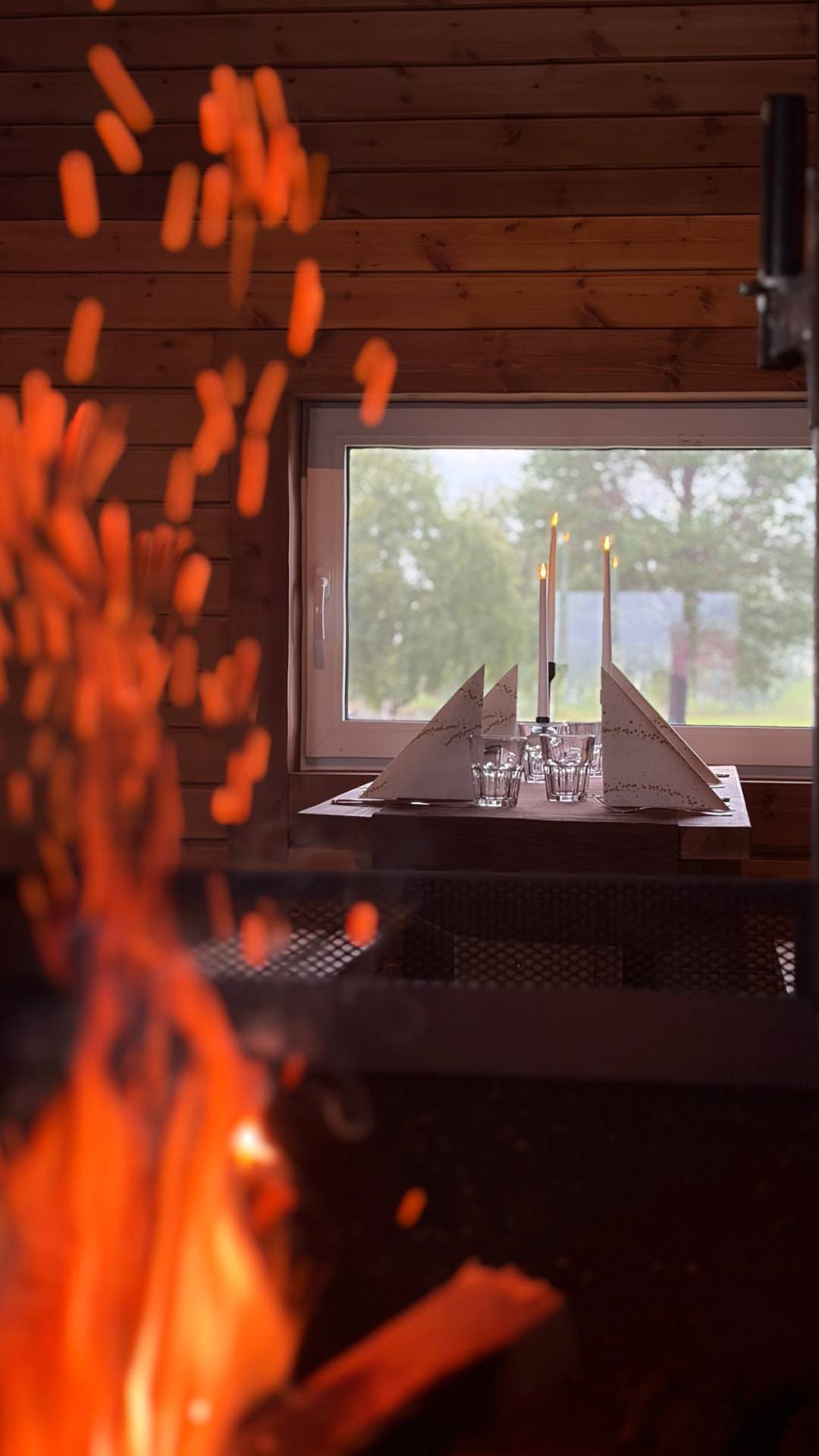 Étincelles du feu et table dressée près de la fenêtre